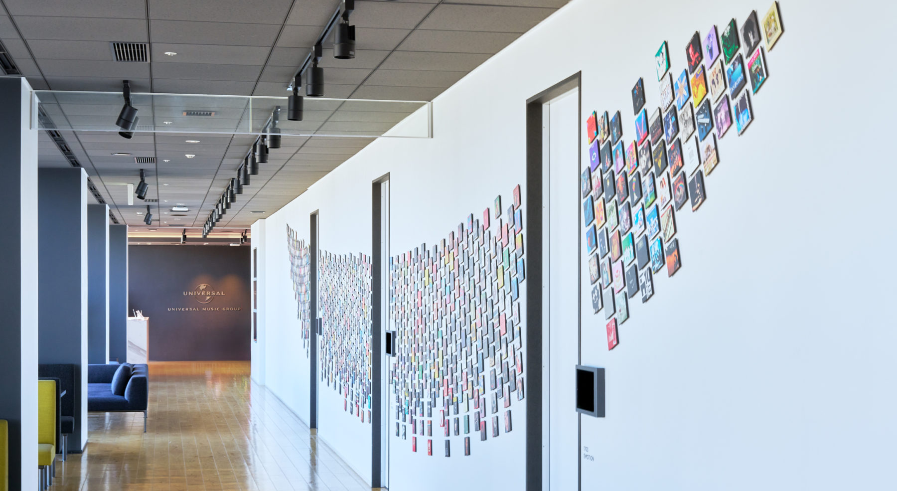 世界60以上の国と地域で音楽ビジネスを展開するユニバーサルミュージック ジャパンのインナーブランディングプロジェクトに参画しました。組織拡大や合併による企業文化の希薄化、音楽ビジネス環境および事業領域の大きな変化を背景に、これまでの成功体験に留まらず、次の成長フェーズへ進むことが求められていました。社員一人ひとりが一体感を持って会社の変革を自分事として捉え、意識と行動のベクトルを揃えるため、同社の意志を体現する一貫したコンセプトおよびストーリー設計を行いました。<br />
<br />
ヒアリングとリサーチを通じて導き出した軸は、「アーティストファースト」という思想の再解釈です。社員を支え続ける存在として捉え、アーティストとの距離感や関係性を可視化するコンセプトを構築しました。そのコンセプトをもとに、オフィス内の象徴的な場であるウォールアートをはじめ、空間、プロダクト、映像へと横断的に展開しています。<br />
<br />
日常の動線や業務のなかで思想に継続的に触れられる体験を設計することで、スローガンに留まらず、無意識下で社員の意識と行動に浸透するインナーブランディングを実現しました。人と企業の関係構築であるインナーブランディングは少し先を見据えて何が必要かをつねに考えアップデートしていく必要があり、これからもメインウォールアートを軸とし、社員増加、企業の成長とともに進化し続けるブランド表現を目指しました。