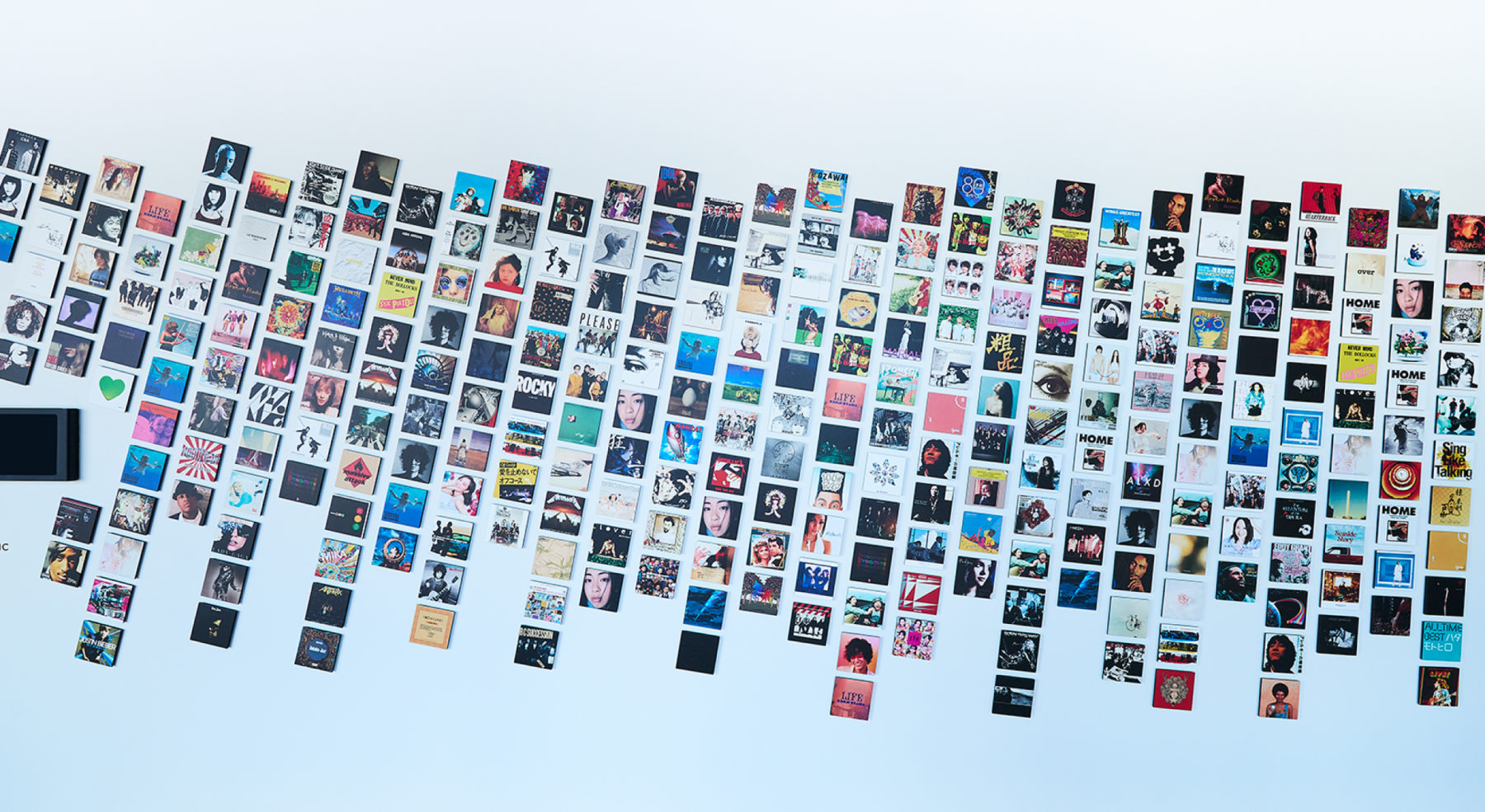 Entrance Installation「PERILUNE NOTES」<br />
<br />
オフィス17階のエントランスから続く長い廊下には、数多くの作品ジャケットで構成されたインスタレーションが設置され、行き交う人々の会話が自然と生まれる、コミュニケーションの起点となっていました。今回のインナーブランディングプロジェクトに合わせ、この場を改めて社員の心を一つにする象徴的な存在とするため、ウォールのリニューアルを行いました。<br />
<br />
全体のコンセプトに呼応し、「PERILUNE NOTES（ペリルーン・ノーツ）」と名付けられたこのウォールでは、社員によって選ばれたジャケットを、月の公転による楕円軌道になぞらえて配置しています。また社員の増加にあわせてジャケットを追加していくことができる、更新性を備えたウォールとして設計されており、時間とともに変化し続けるインスタレーションとなっています。